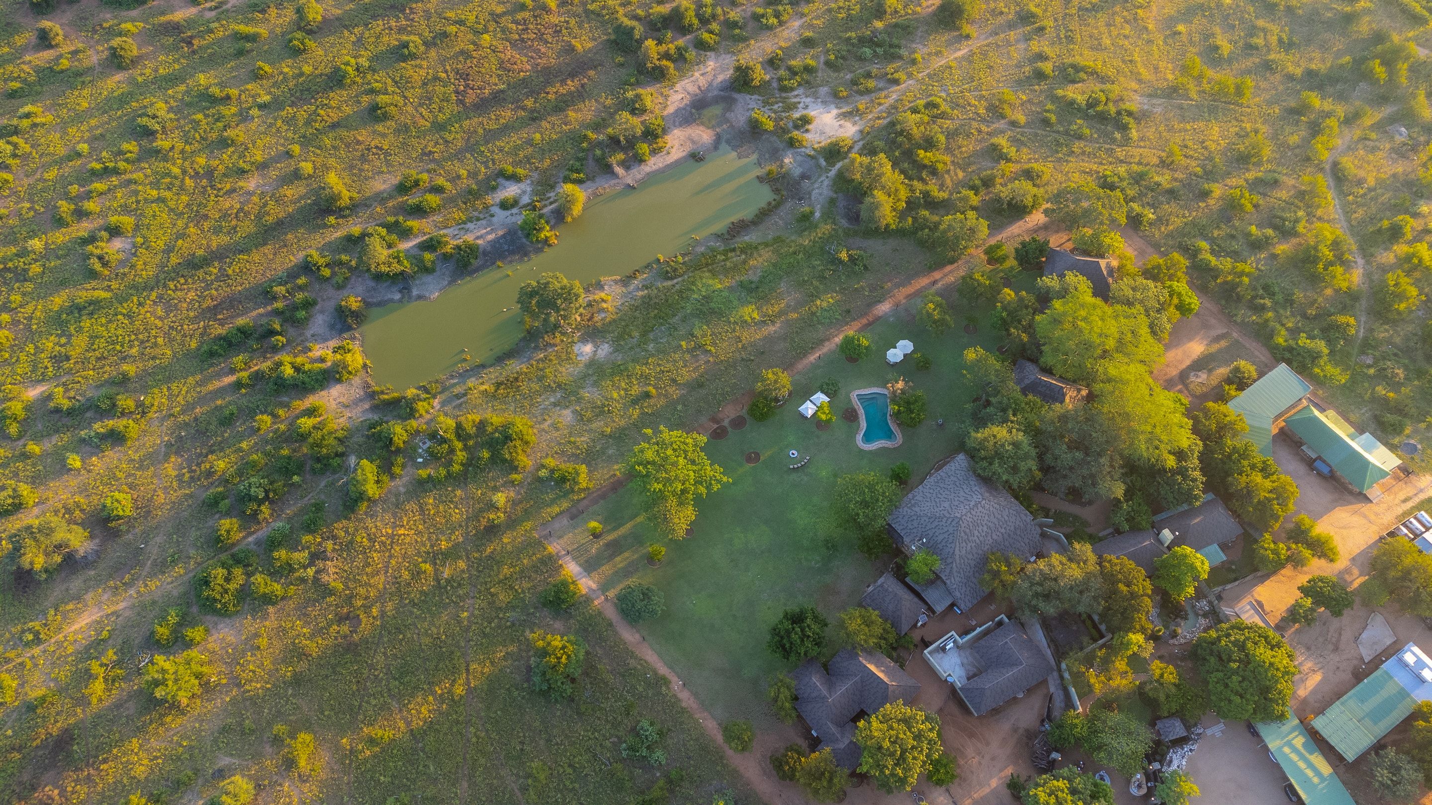 Aerial view of Nzumba Lodge chalets clustered beside the waterhole in the Klaserie bushveld