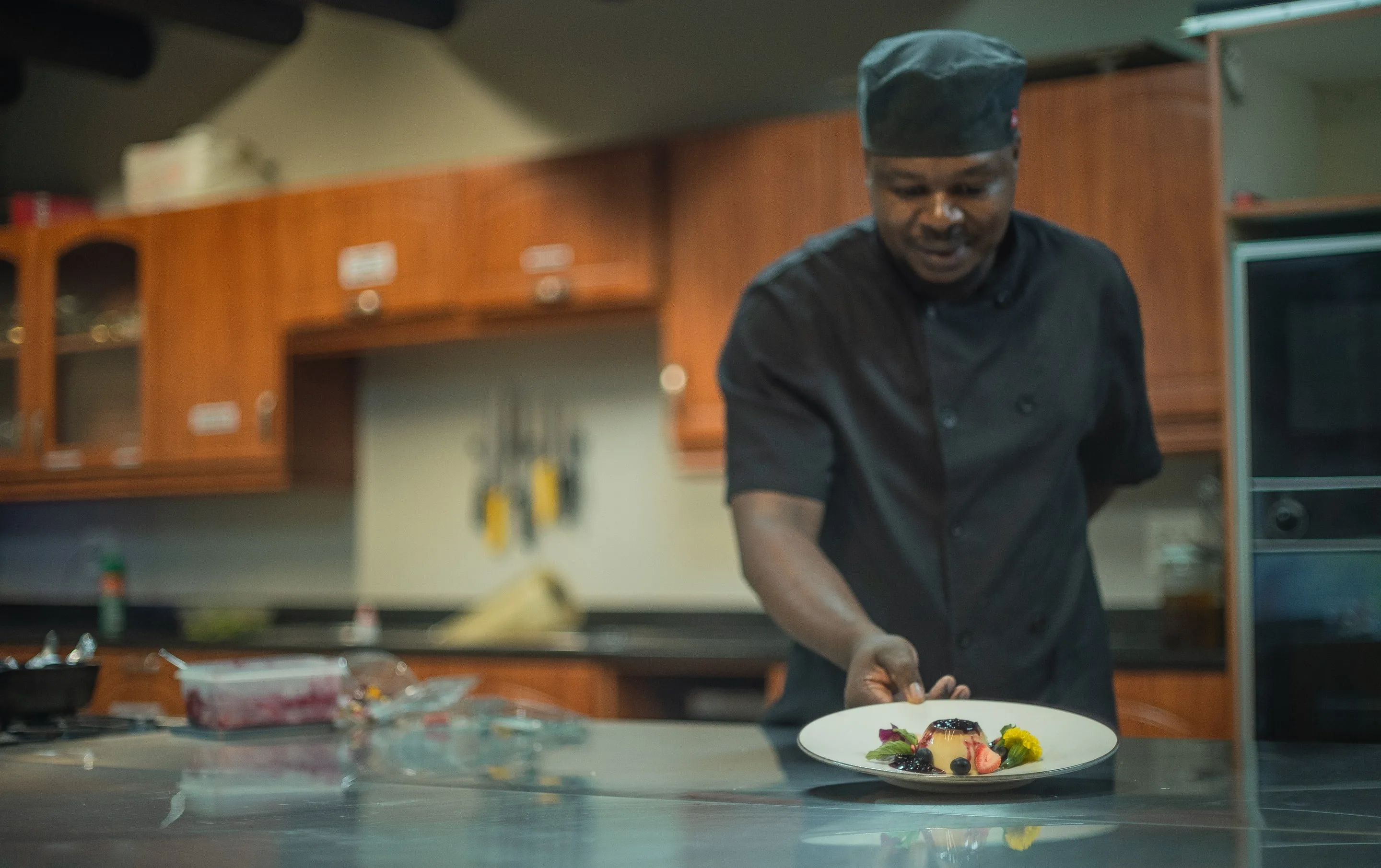 Nzumba chef plating a course in the kitchen