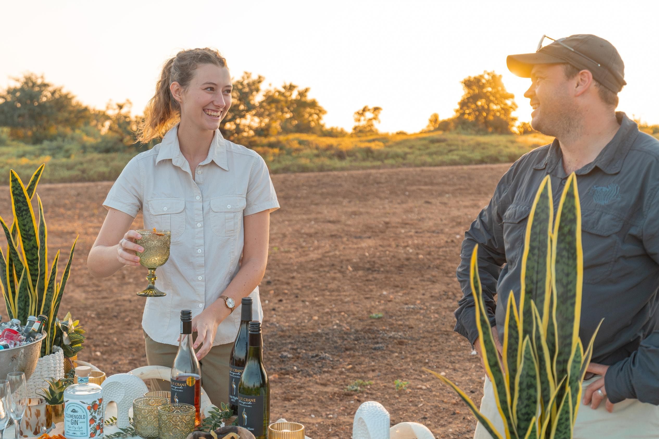 Nzumba staff laying out drinks and snacks at a bush sundowner