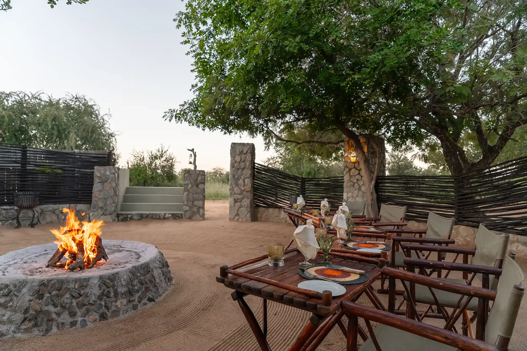 A boma dinner setting at Nzumba Lodge with lanterns, candles and an open fire