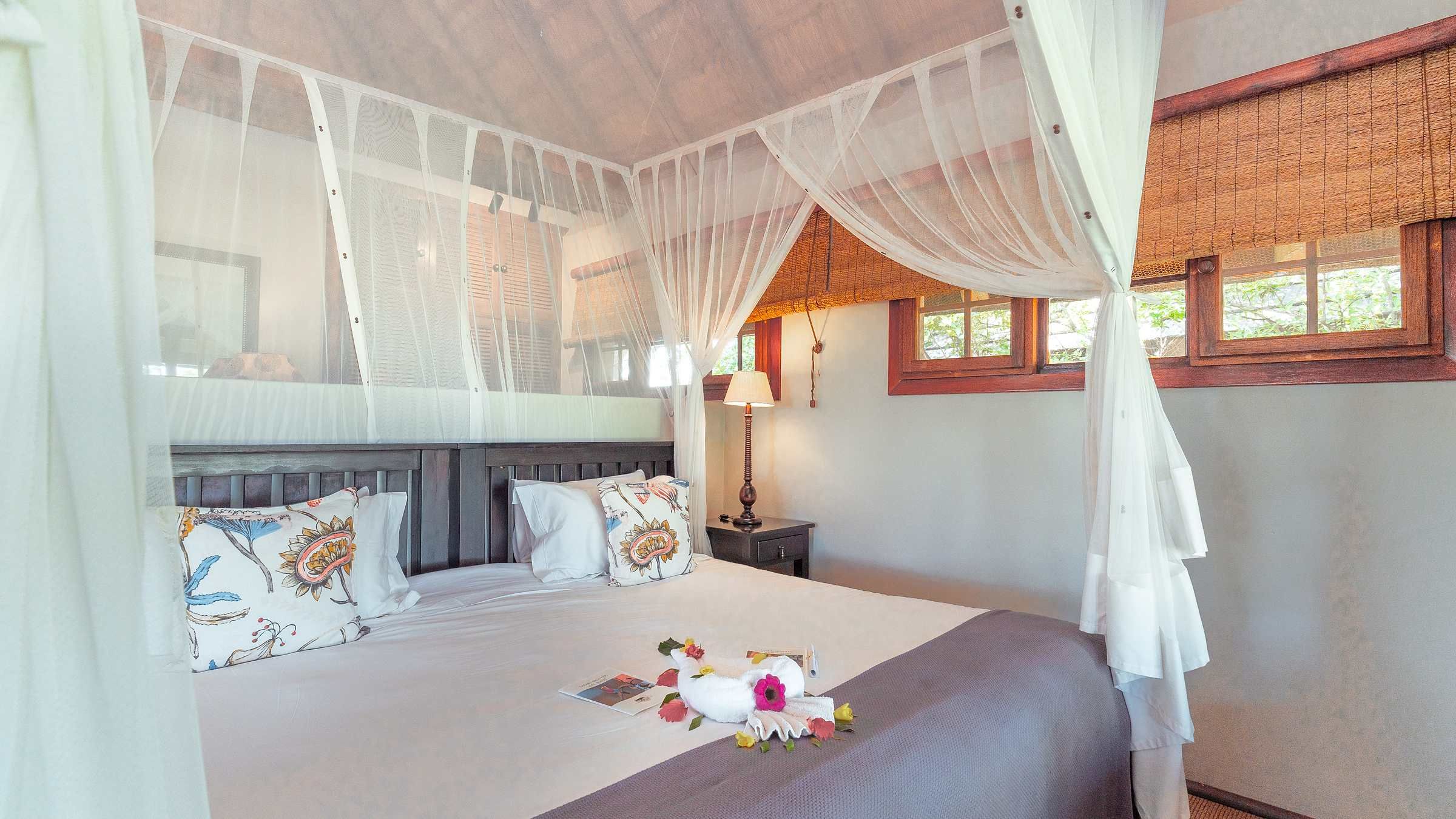 Overhead aerial view of the Nzumba Lodge chalets clustered beside the green waterhole