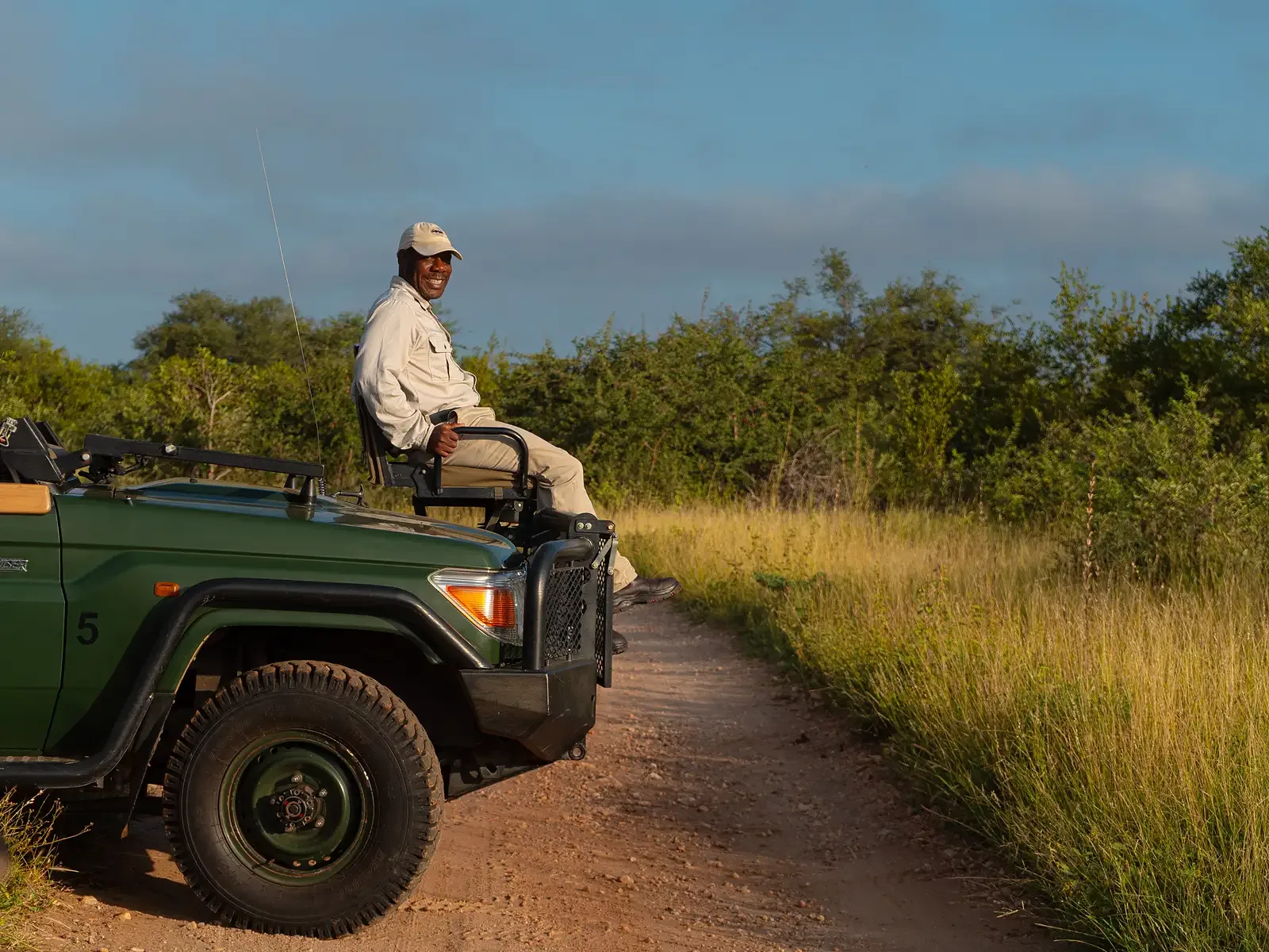 Nzumba guide pointing out wildlife from the game-drive vehicle