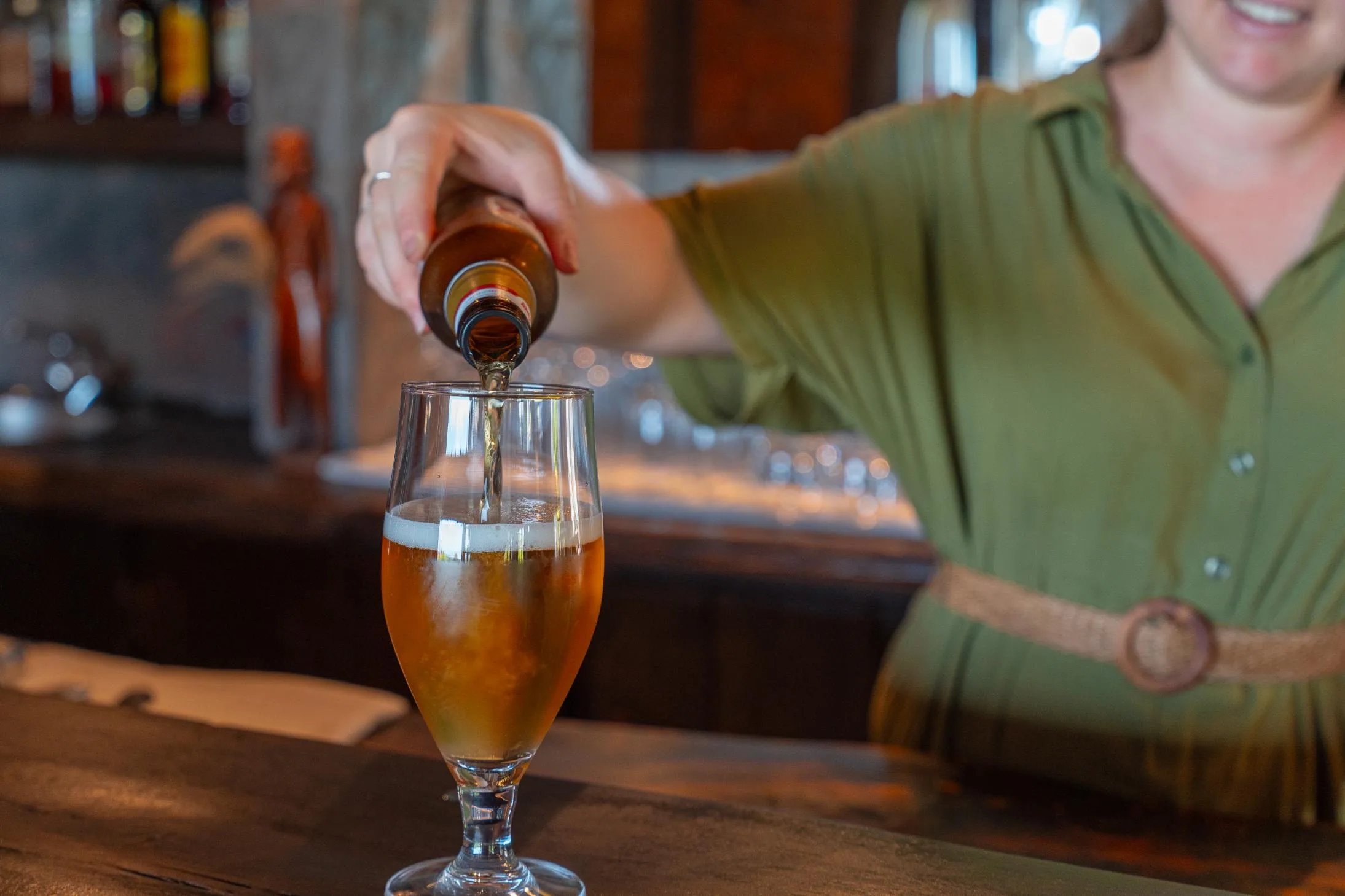 The Nzumba Lodge bar — bottles and glassware against rough-cut timber