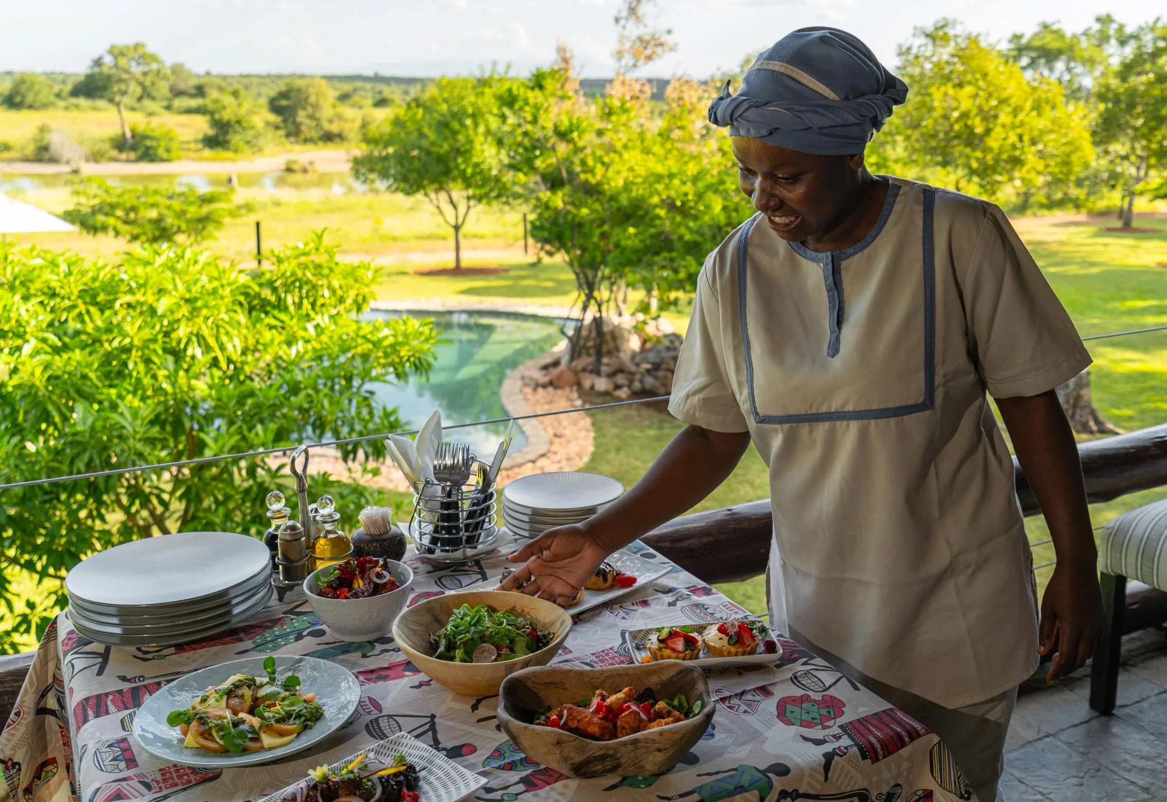 A Nzumba team member serving a bush breakfast spread outdoors