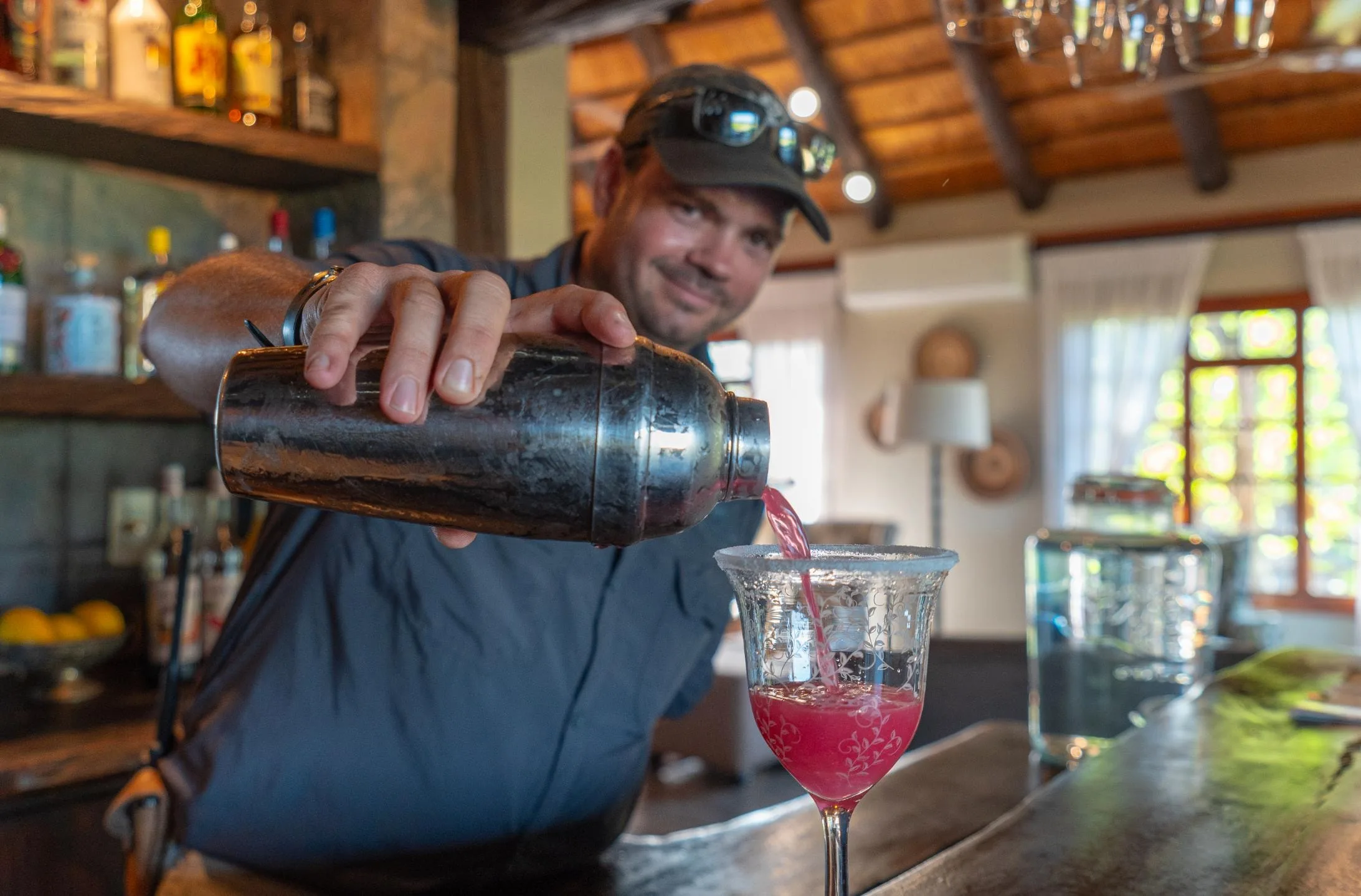 The bar at Nzumba Lodge — timber, bottles and warm lamplight
