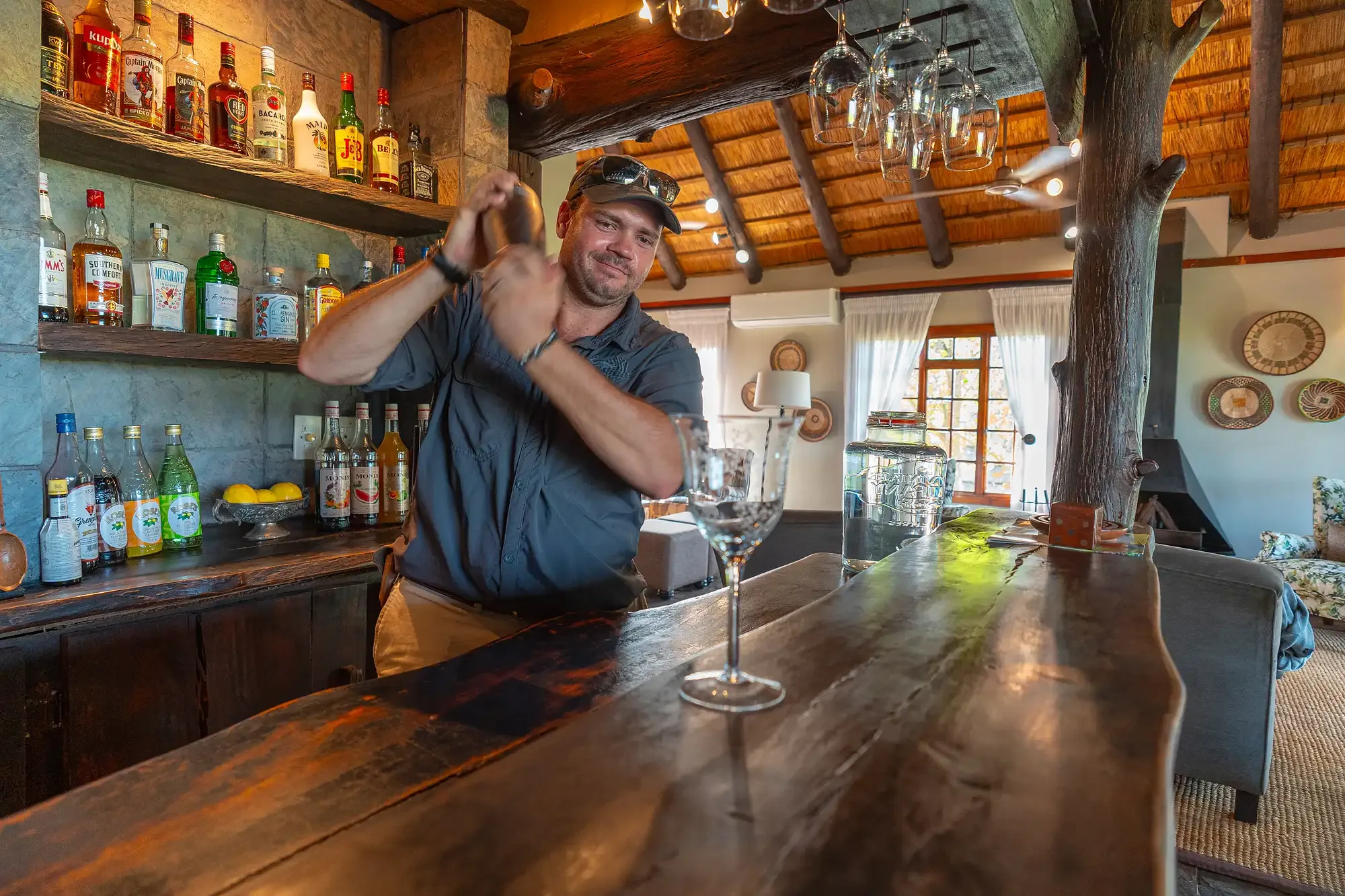The bar at Nzumba Lodge — timber, bottles and warm lamplight