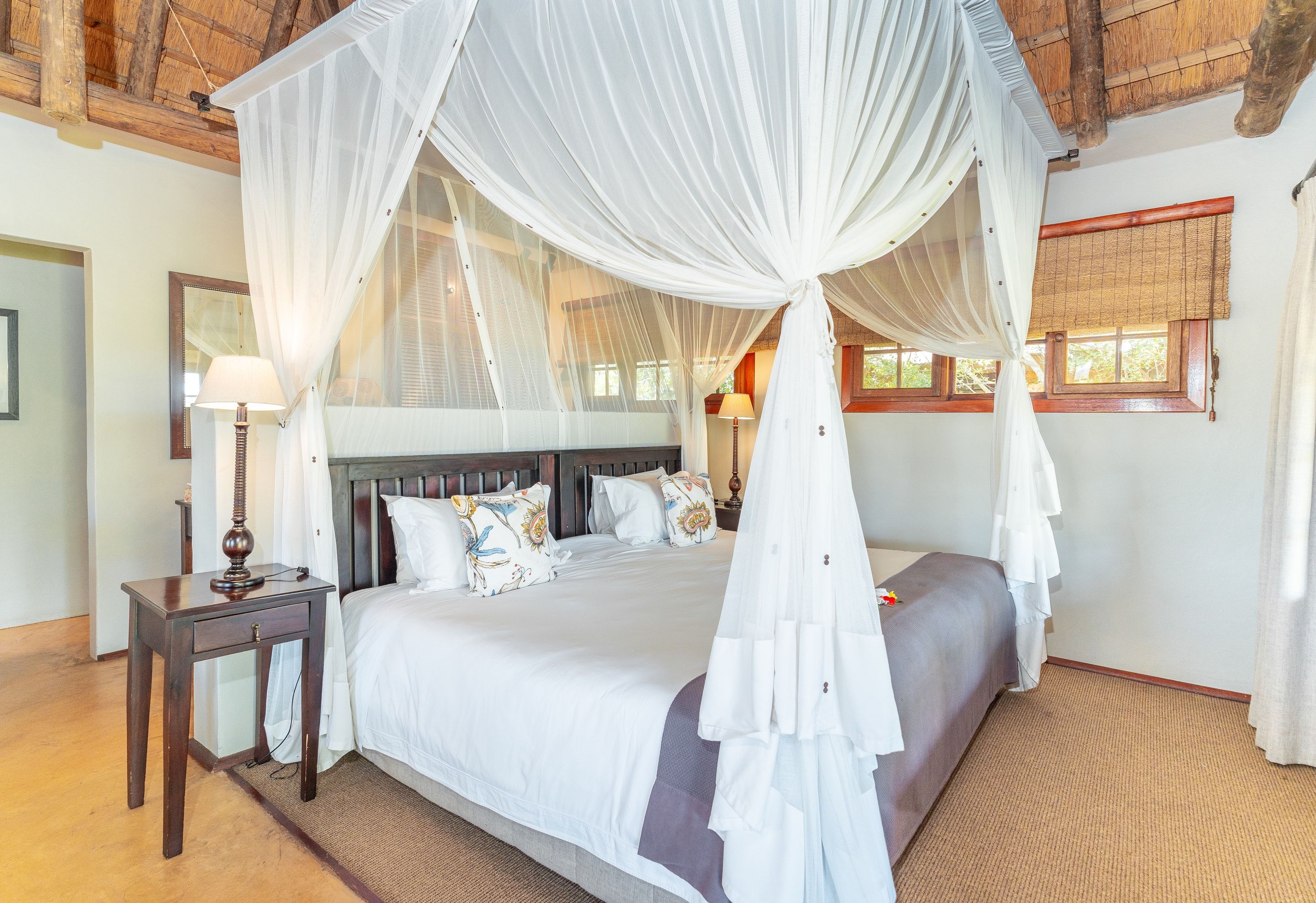 A canopied four-poster bed inside a Nzumba Lodge thatched chalet