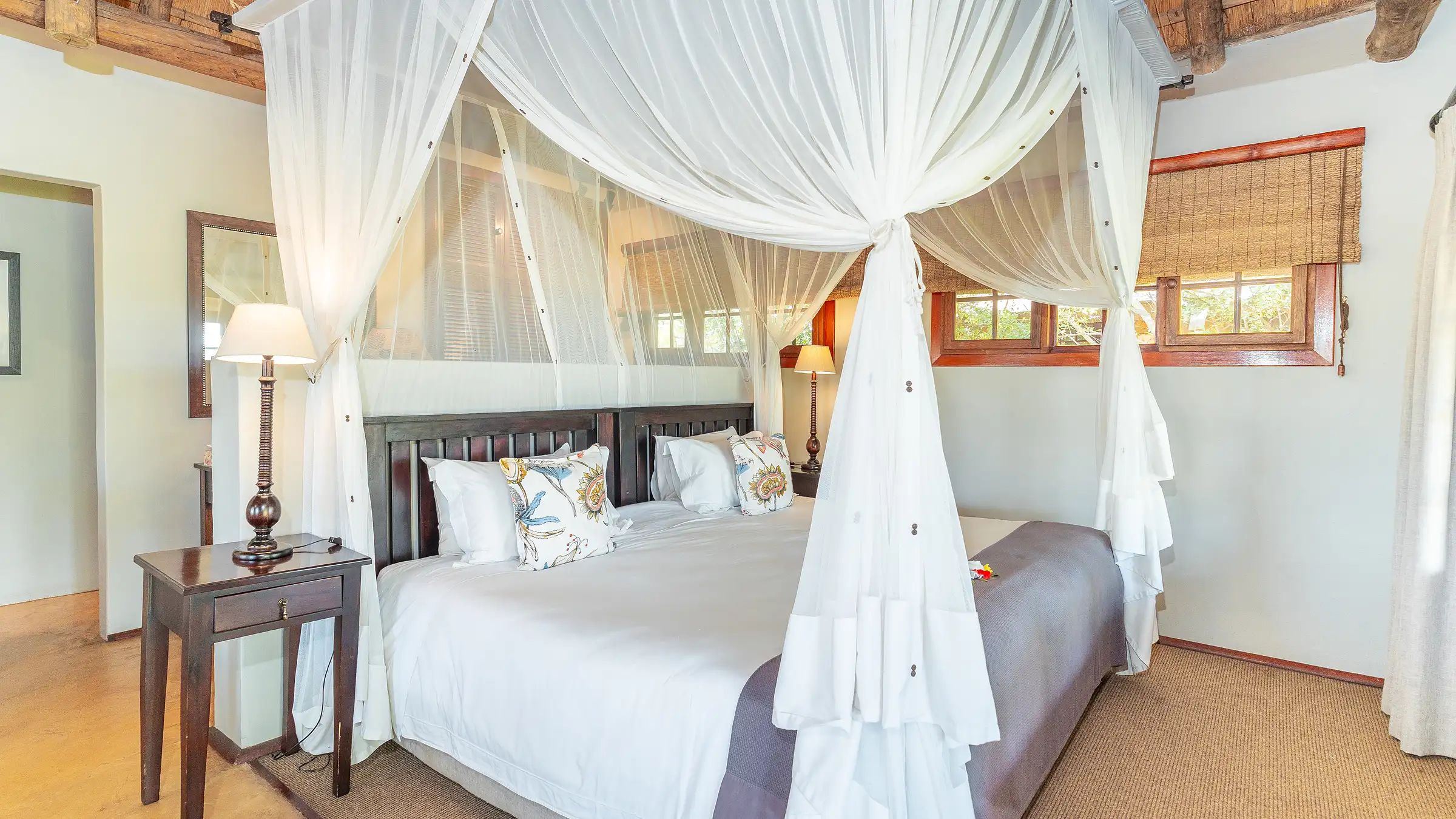 A canopied four-poster bed inside a Nzumba Lodge thatched chalet