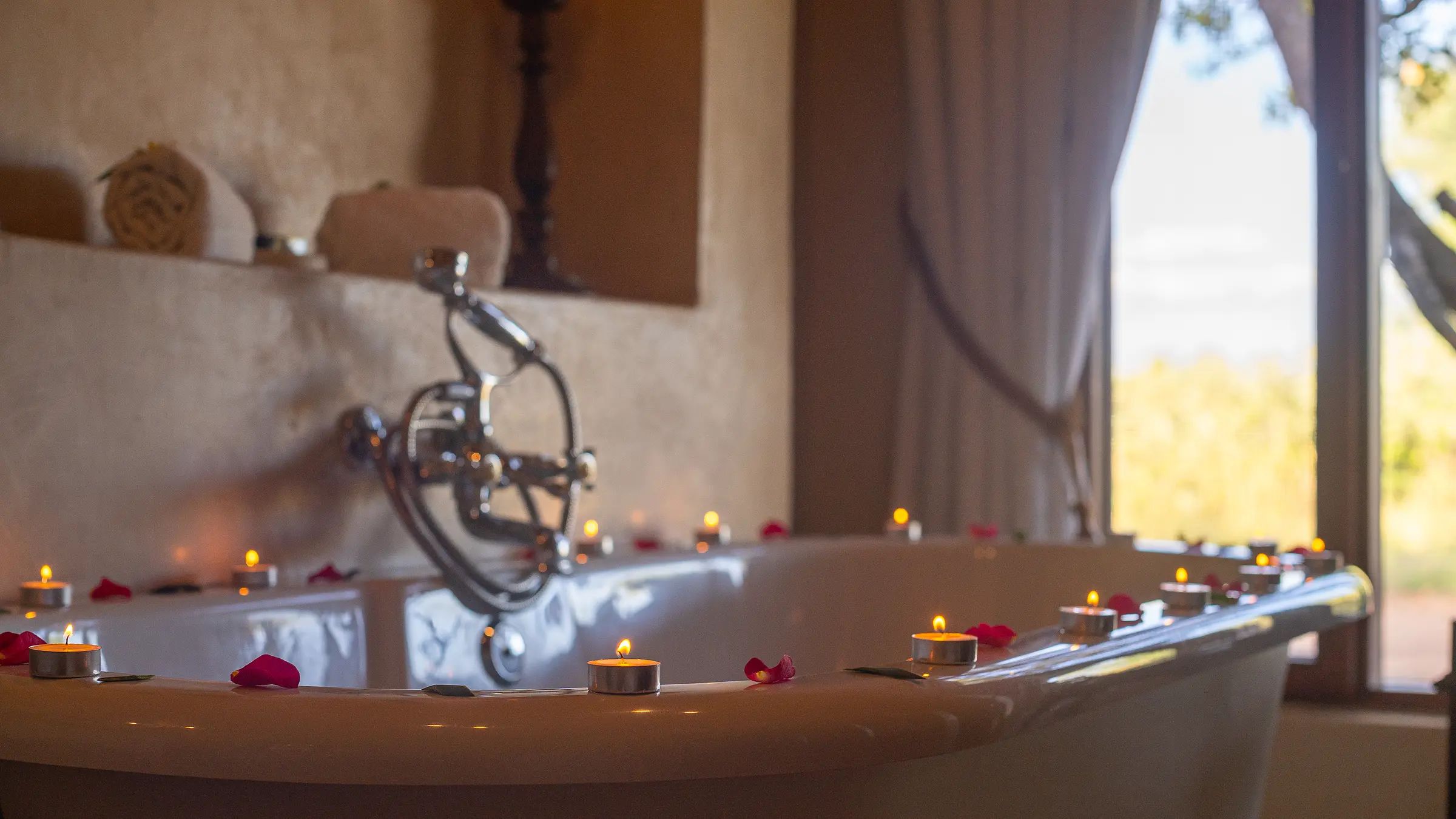 A free-standing bathtub at Nzumba Lodge with a bushveld view through the window