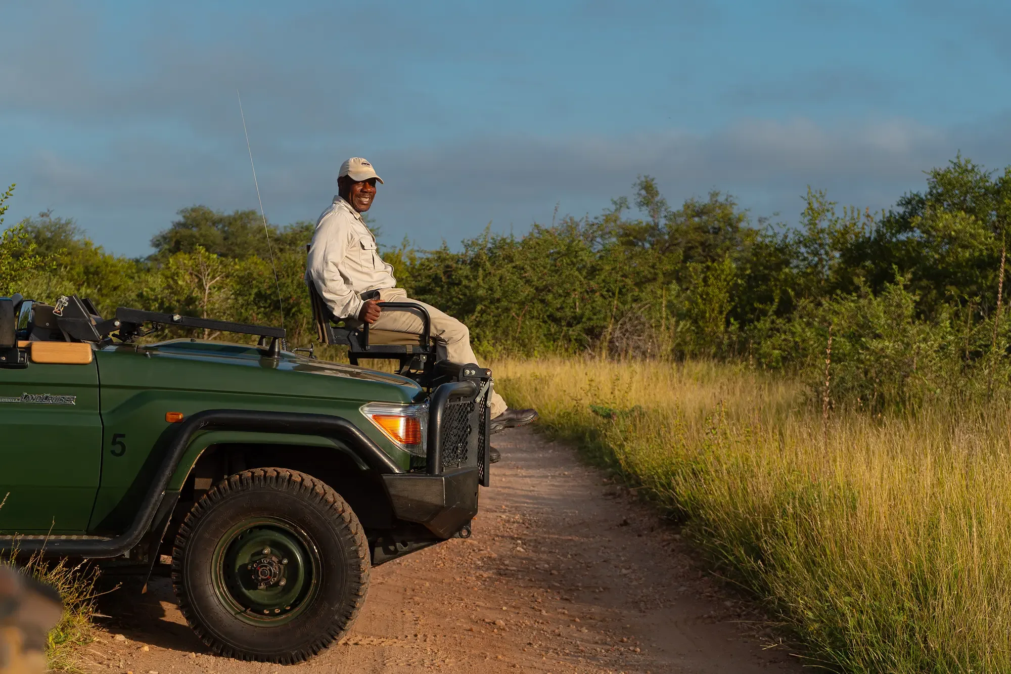 A Nzumba Lodge tracker seated on the front of the open game-drive vehicle
